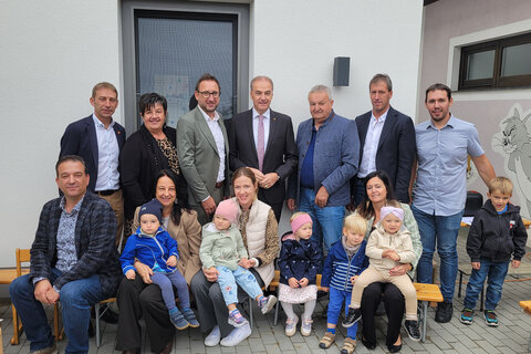 Landesrat Dr. Leonhard Schneemann (Mitte, hinten) bei der Eröffnung der neuen Kinderkrippe mit Ehrengästen sowie Müttern mit ihren Kindern in St. Michael.