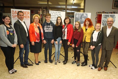 Landtagspräsidentin Verena Dunst (3.v.l.), Thomas König (2.v.l.), Lehrerin Renate Fandl (5.v.r.), Direktor Gerd Kirschner, BEd.MSc (r.) und Schulqualitätsmanagerin (SQM), Reg.Rätin Gerlinde Potetz (3.v.r.) mit Schülerinnen und Schülern vor Tafeln der Wanderausstellung.