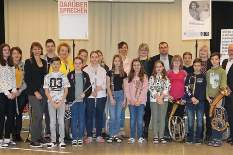 Landtagspräsidentin Verena Dunst (6.v.l.), Direktorin Daniela Hallemann, BEd, MA (3.v.l.), Vizebürgermeister Christoph Kovacs (3.v.r. hinten) und Referent OSR Knut Becha, Bildungsdirektion (r.) mit Schülerinnen und Schülern der NMS Markt Allhau, die die Veranstaltung instrumentalisch begleiteten.