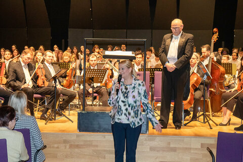 Landesrätin Mag.a (FH) Daniela Winkler mit Dirigent und Projektleiter Anton Gabmayer sowie Schülerinnen und Schülern des schulübergreifenden Projektchors.