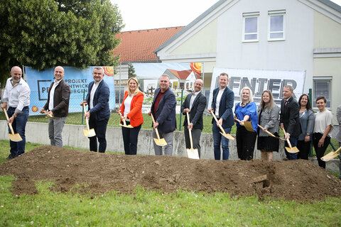 Spatenstich mit Landesrat Mag. Heinrich Dorner (4.v.l.) sowie Bildungs-Landesrätin Mag.a (FH) Daniela Winkler (5.v.l.) mit Gemeinderätinnen und Gemeinderäten sowie Mitarbeiterinnen und Mitarbeitern der bauausführenden Firma.