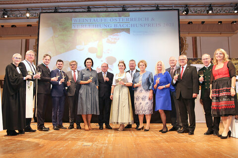 Anstoßen mit dem getauften Weinjahrgang 2021. Evangel. Pfarrerin Ingrid Tschank, Pfarrer Günter Kroiss, Johannes Schmuckenschlager, Präsident des Österreichischen Weinbauverbandes, Winzer Tobias Siess, Winzer Gerhard Wohlmuth., BM Elisabeth Köstinger, Weinbaupräsident Andreas Liegenfeld, Bundesweinkönigin Diana I., Chris Yorke, Geschäftsführer der Österreich Wein Marketing GmbH., Lt-Präs.in Verena Dunst, Bacchuspreisträgerin MW Caro Maurer, Ehrenringträger Franz Backknecht, Bacchuspreisträger LH a.D. Hans Niessl, Ehrenringträger Johann Dreisiebner, Moderatorin Birgit Perl