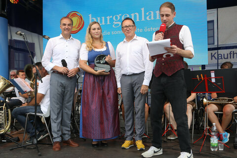 Frühschoppen Stadtschlaining: Preisverleihung auf der Bühne mit Landesrat Dr. Leonhard Schneemann, Kapellmeisterin Laura Divosch, Obmann DI Peter Reichstädter und Moderator Thomas Hochwarter vom ORF Burgenland (v.l.).