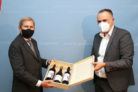 Landeshauptmann Mag. Hans Peter Doskozil überreicht EU-Kommissar Dr. Johannes Hahn bei der Begrüßung in seinen Amtsräumen Wein aus dem Burgenland als Willkommensgeschenk