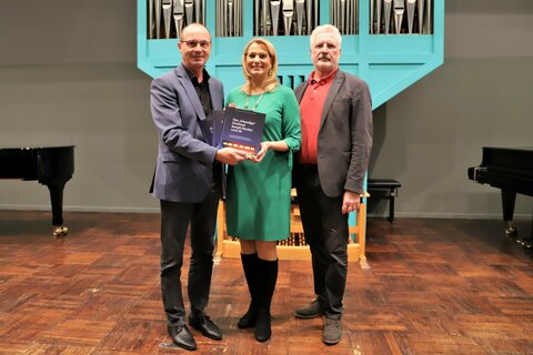 Landesrätin Mag.a (FH) Daniela Winkler (Mitte) nahm, im Rahmen des Kick Offs des Schulmusikwettbewerbs, die Festschrift zum 50-jährigen Bestehen des Joseph Haydn Konservatoriums entgegen – überreicht von Joseph Haydn Konservatorium-Geschäftsführer Mag. Franz Steindl (l.) und -Direktor Prof. Mag. Tibor Nemeth (r.).