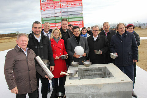 Bei der Grundsteinlegung für das Zentrallagerprojekt des Möbelhauses XXXLutz in Zurndorf wurde eine von Landesrat Christian Illedits in Vertretung von Landeshauptmann Hans Peter Doskozil, Landeshauptmann a.D. Hans Niessl, Landesrätin Mag.a (FH) Daniela Winkler, Landesrat Heinrich Dorner, Landesrat MMag. Alexander Petschnig, Bgm. LAbg. Werner Friedl, XXXLutz Unternehmenssprecher Mag. Thomas Saliger und Dr. Alois Knauseder, Leiter der XXXLutz Bauabteilung, unterzeichnete Urkunde in das Fundament einbetoniert