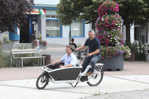 Landesrat Mag. Heinrich Dorner probierte gemeinsam mit Bürgermeister Mag. Gert Polster ein Cargobike am Hauptplatz von Bad Tatzmannsdorf aus.