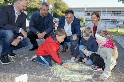 VS Stoob Straßenmalwettbewerb „Blühende Straßen“: Nico, Milan und Grace, alle 1. Klasse VS Stoob, malen mit großer Begeisterung frisch darauf los, sehr zur Freude von Verkehrslandesrat Heinrich Dorner, Stoobs Bürgermeister Bruno Stutzenstein (4.v.l.), Schulleiter Simon Horvath (l.), und Tina Wurm von der Mobilitätszentrale Burgenland