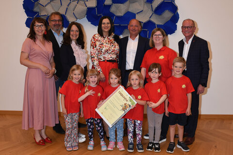 Gruppenbild von der Jubiläumsfeier 50 Jahre Kindergarten Kobersdorf mit (v.l.) Vizebürgermeisterin Mag.a Natascha Thurner, DI Thomas Böhm, Vizepräsident Verband der Naturparke Österreichs, Julia Friedlmayer, Geschäftsführerin Verband der Naturparke Österreichs, Landeshauptmann-Stellvertreterin Mag.a Astrid Eisenkopf, Kobersdorfs Bürgermeister Andreas Tremmel, Christine Fleck, Kindergartenleiterin und Bürgermeister Horst Egresich, Kaisersdorf, mit Kindern.