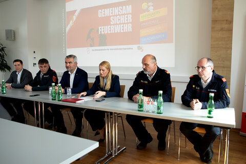 Landesrat Feuerwehrreferent Heinrich Dorner (3.v.l.), Bildungslandesrätin Daniela Winkler (3.v.r.), Landesfeuerwehrkommandant Franz Kropf (2.v.r.), Pinkafelds Feuerwehrkommandant Kurt Zapfel (2.v.l.), Schulqualitätsmanager Daniel Baumann (l.) und Adolf Selinger (r.) stellten das Projekt im Feuerwehrhaus Pinkafeld vor.