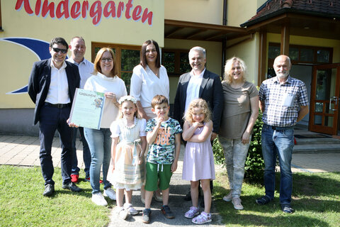 Landeshauptmann-Stv. Mag.a Astrid Eisenkopf (4.v.l. hinten) überreichte gemeinsam mit Geschäftsführer Franz Handler (l.)  vom Verband der Naturparke Österreichs und Bürgermeister Christian Pinzker (3.v.r. stehend) die Naturpark-Kindergarten-Urkunde an Holzschlags Kindergarten-Leiterin Katharina Schranz (3.v.l.).