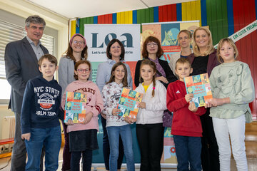 Schulqualitätsmanager Werner Zwickl, MSc, Alexandra Wolk, stellvertretende Direktorin von LEA, Volksschuldirektorin Kordula Csukker, BEd. MA, Autorin Raffaela Schöbitz, LEA-Projektmanagerin Katja Grafl und Bildungslandesrätin Mag.a (FH) Daniela Winkler mit Schüler*innen der VS Am Tabor.