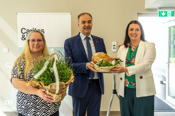 Landesrat Dr. Leonhard Schneemann (Mitte) übergab Brot und Salz an Caritas-Direktorin Melanie Balaskovics (r.) und Bereichsleiterin Lisa Milkovits (l.) im Zuge der Eröffnung.