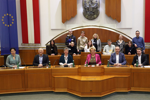 DDr. Barbara Glück (l., vorne) und Landtagspräsidentin Verena Dunst (4.v.r., vorne) sowie Auslandsdiener Jonathan Dorner (2.v.r., vorne) mit Grünen Klubobfrau Mag.a Regina Petrik (3.v.l.), den Landtagsabgeordneten Gerhard Bachmann (2.v.r., vorne) und Gerald Handig (2.v.l., vorne) sowie den Schülerinnen und Schülern der Klasse 7c.