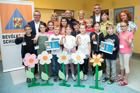 Gruppenbild bei der Präsentation der Initiative „Gefahren erkennen und vermeiden“ mit (stehend hinten v.l.) Mag. Franz Bock, Schulqualitätsmanager, Bildungsdirektion Burgenland, Dipl. Päd. VDir. OSR Eva Scheibstock, Präsident des Bevölkerungsschutz Mag. Herbert Wagner, MSc, MBA, Landesrätin Mag. (FH) Daniela Winkler, Landesrat Mag. Heinrich Dorner, Rosemarie Harter, Gemeindevorständin, Vizebürgermeisterin Mag. Monika Teubenbacher-Schriefl und Schüler*innen der Volksschule Müllendorf.