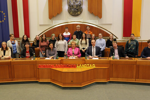 Landtagspräsidentin Verena Dunst (vorne, Mitte), Landesrat Dr. Leonhard Schneemann (3.v.r., vorne) sowie DDr. Barbara Glück (3.v.l, vorne) und Auslandsdiener Jonathan Dorner (3.v.r., vorne) mit Schülerinnen und Schülern der 7.a Klasse POP-und KOM-Zweig sowie Lehrerin Prof.in Bettina Koller (2.v.l. stehend) des Wimmer Gymnasiums Oberschützen.