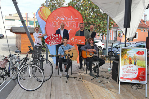 Die Band „The Blamphins“ – im Bild zwei Bandmitglieder – wird die Tour über 220 km auf dem Rad und musikalisch begleiten. V.l.: DI Christine Zopf-Renner, Leiterin der Mobilitätszentrale Burgenland, Mag. Peter Zinggl, Gesamtverkehrskoordinator Burgenland, Tom Oriovics, LR Mag. Heinrich Dorner, Steve Smith, Michael Bauer von der Agentur katapult