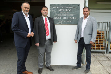 Landeshauptmann Hans Peter Doskozil mit Bürgermeister Marc Hoppel und Vizebürgermeister Johannes Pfeffer (v.l.) vor der Gedenktafel der neuen Veranstaltungshalle, die vom verstorbenen Vizebürgermeister Ernst Michalek geplant und erbaut wurde.