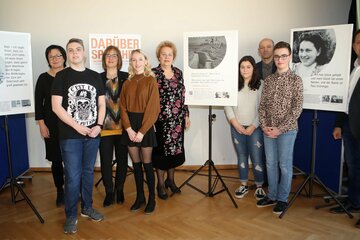 Landtagspräsidentin Verena Dunst (Mitte), Freizeitpädagoge und Tischlermeister Thomas König (r.), Direktorin Mag. Karin Schneemann (ECOLE) (3.v.l.), Lisbeth Bachmann (l.) und Direktor Robert Antoni (BORG) mit Jugendlichen der beiden Schulen vor Tafeln der Wanderausstellung.