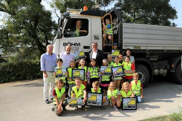 Bildungslandesrätin Mag.a (FH) Daniela Winkler (hinten Mitte, im LKW) mit Transportunternehmen-Geschäftsleiter Günter Böhm, Mag. Heinz Josef Zitz, Bildungsdirektor für das Burgenland, und Mag. Roman Eder, MBA, Fachgruppenobmann für Güterbeförderungsgewerbe der Wirtschaftskammer Burgenland, (3. Reihe v. l. n. r.) sowie Schuldirektorin Kordula Csukker, BEd. MA, (3. Reihe r.) und Schülerinnen und Schüler der dritten Klasse der Volksschule am Tabor in Neusiedl am See.