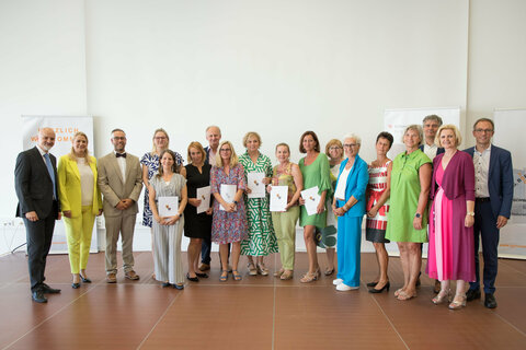 Gruppenbild der Pädagoginnen und Pädagogen des Bezirks Neusiedl am See, die beim Empfang für Neupädagoginnen und Neupädagogen eine Auszeichnung bzw. ihr Pensionierungsdekret erhalten haben, mit Landesrätin Daniela Winkler (2.v.l.) und Bildungsdirektor Heinz Josef Zitz (1.v.l.).