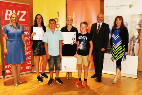 Landesrätin Mag.a(FH) Daniela Winkler (l.) und Bildungsdirektor Mag. Heinz Josef Zitz gratulierten Schulleiterin Elisabeth Szuppin, Pädagogin Irina Blühberger sowie den Schülern Jörg und Darius zur Auszeichnung