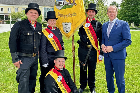 LR Dr. Leonhard Schneemann und Landesinnungsmeister Herbert Baumrock mit neuen Rauchfangkehrermeister*innen und der Innungsfahne.