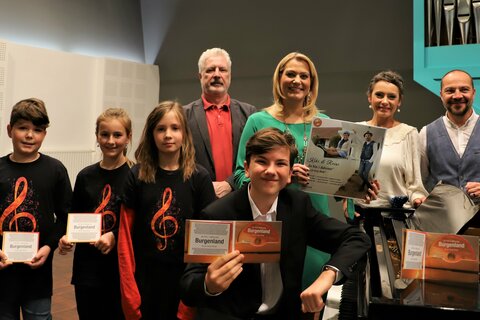 andesrätin Mag.a (FH) Daniela Winkler gemeinsam mit Kristina Buconjic und Reinhold Bieber sowie Konservatorium-Direktor Prof. Mag. Tibor Nemeth, Enrico Sieber und Mitwirkenden am Schulchor der Neuen Mittelschule Horitschon.