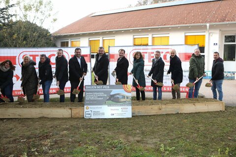 Landesrat Mag. Heinrich Dorner (Mitte) flankiert von Bürgermeister Gert Polster (r.) und Vizebürgermeister Stefan Laimer (l.) sowie weitere Beteiligte beim Spatenstich für die Volksschule und den Kindergarten in Bad Tatzmannsdorf.