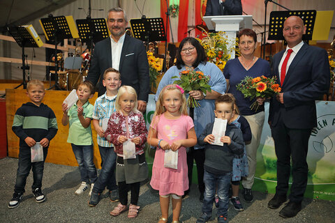 Die Kindergartenkinder sangen gemeinsam mit ihrer Kindergartenleiterin Manuela Stifter (hinten, 2.v.l.) und Erika Sachs (hinten, 2.v.r.) Lieder beim Festakt. Danach wurden ihnen von Landesrat Mag. Heinrich Dorner (hinten, l.) und Bürgermeister Andreas Tremmel (hinten, r.) Geschenke sowie Blumen überreicht.