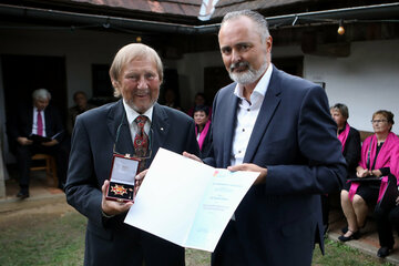 Anlässlich des 80. Geburtstages von Prof. Gerhard Kisser, dem Gründer des Freilichtmuseums Ensemble Gerersdorf, fand gestern ein Festakt im Freilichtmuseum statt. „Mit außergewöhnlichem Fleiß und Engagement hat sich Gerhard Kisser herausragende Verdienste um das Kulturland Burgenland erworben, hat den erfolgreichen burgenländischen Weg entscheidend mitgeprägt. Es freut mich sehr, ihm genau am Tag seines 80. Geburtstages, das Große Goldene Ehrenzeichen des Landes Burgenland überreichen zu dürfen“, betonte Landeshauptmann Hans Peter Doskozil beim Festakt in Gerersdorf. Wenn das Burgenland heuer sein 100-jähriges Jubiläum feiert, stehen Kultur und Volkskultur verstärkt im Mittelpunkt. „Gerhard Kisser spiegelt mit dem Freilichtmuseum eindrucksvoll die Identität und Vielfalt unseres Landes wider, schafft ein verstärktes Burgenland-Bewusstsein und macht die historischen Wurzeln greifbar“, so der Landeshauptmann.   Untrennbar mit der Geschichte des Landes verbunden ist das Freilichtmuseum Ensemble Gerersdorf, das mit seinen jährlich rund 11.000 Besucherinnen und Besuchern eine der größten Sehenswürdigkeiten des Südburgenlandes darstellt, dabei Einblicke in die pannonische Kultur der letzten drei Jahrhunderte gewährt und Besucherinnen und Besuchern burgenländische Volkskultur hautnah vermittelt. Die 32 Objekte, meist strohgedeckte uralte Wohn- und Wirtschaftsgebäude, beherbergen eine Fülle von bodenständigen Gebrauchsgegenständen und bäuerlichen Gerätschaften. Damit erwecken sie einen Eindruck, wie all die Menschen früher im Land gelebt und gearbeitet haben und sich der Alltag im Laufe der letzten Jahrhunderte verändert hat.  Sanierung der denkmalgeschützten Gebäude  Das „Ensemble Gerersdorf“ wuchs im Laufe der Jahre zu einem „Dorf im Dorf“ und schließlich zum größten Freilichtmuseum des Landessüden. „Ich möchte dem Gründer des Freilichtmuseums, Prof. Gerhard Kisser, für die Erhaltung dieser wichtigen Kulturstätte danken. Kulturgeschichtlich wertvolle Holzblockbauten konnten hierher übertragen und damit vor dem endgültigen Verfall gerettet werden“, würdigte Doskozil die Arbeit Kissers, der sich 2014 mit seiner Ehefrau Eveline im Burgenland niedergelassen hat, „seitens des Landes möchte ich meine vollste Unterstützung bei der Sanierung der vorwiegend denkmalgeschützten musealen Gebäude zusichern“.  Geplant ist die Erneuerung bzw. die Reparatur der Strohdächer, der undichten Ziegeldächer, der Lehmböden und Lehmgredn sowie der Einsatz von Grednbäumen und die Vornahme von Lehmarbeiten am Innen- und Außenverputz. Der Verein „Freunde des Freilichtmuseums Ensemble Gerersdorf bei Güssing“ hat um eine Förderung im Rahmen des Additionalitätsprogramms EFRE angesucht. „Ich bin mir sicher, durch die geplanten denkmalgerechten Sanierungen wird das Image des Museums nachhaltig gestärkt sowie das Museumsangebot vergrößert, um so zusätzliche Anziehungspunkte für Touristen zu schaffen“, so Doskozil abschließend.
