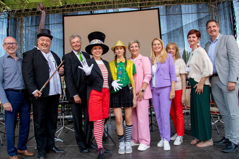 Landesrätin Mag.a (FH) Daniela Winkler, Mattersburgs Bürgermeisterin LAbg. Claudia Schlager, Musikschuldirektorin und Projektleiterin MMag.a Katrin Gstöttenbauer, mit Dirigent Peter Schreiber und den Hauptdarstellern „Nola Note“ Uschi Zezelitsch, „Konrad Kontrabass“ Manfred Schweiger und „Pina Piccolo“ Anna Le Bras-Frenner, die das kleine und große Publikum im Pappelstadion begeisterten, Gerhard Gutschik, dem Geschäftsführer Burgenländisches Musikschulwerks, Schulqualitätsmanagerin Mag.a Michaela Seidl und Mag. Christian Schreiner, dem Direktor des BG/BRG Mattersburg.