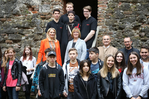 Landesrätin Daniela Winkler, ecole-Direktorin Karin Schneemann, Burgmanager Gilbert Lang und Dieter Szorger, Leiter Hauptreferat Kultur u. Wissenschaft, mit Schülern auf der Burg in Güssing