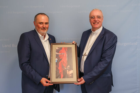 Bischof Ägidius Zsifkovics überreichte Landeshauptmann Hans Peter Doskozil ein Bild, das die Szene darstellt, in der der heilige Martin seinen Mantel mit einem Armen teilt.